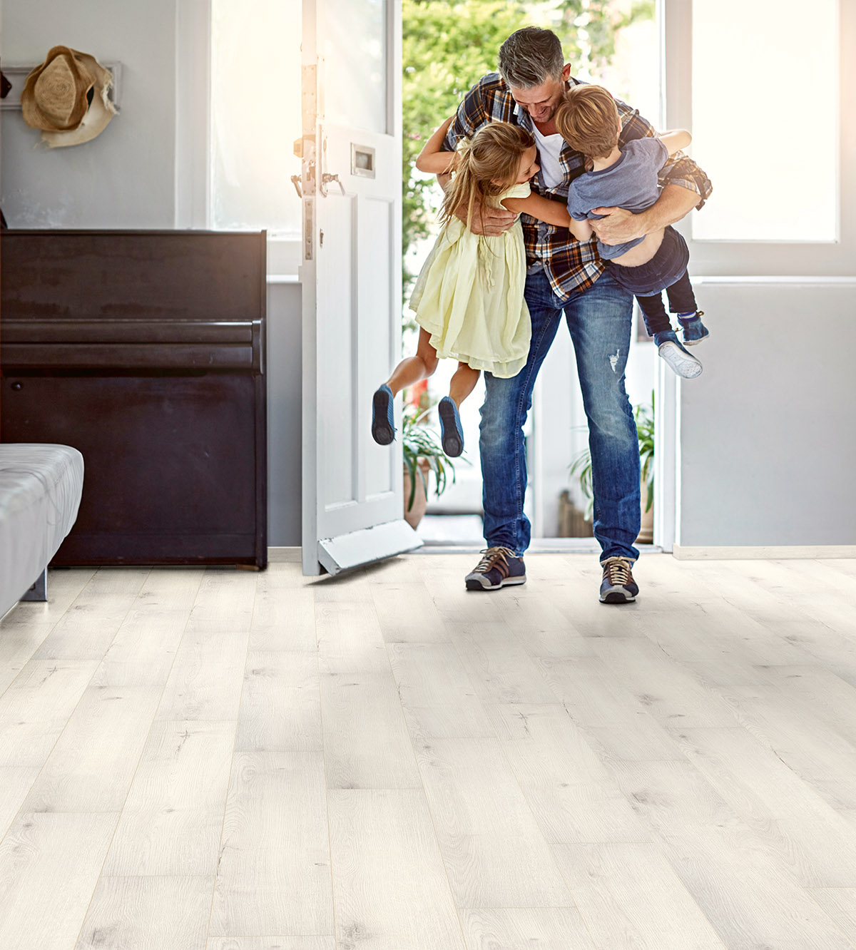 K500 Pearl River Oak oak flooring in a bright entryway as a father comes home and hugs his children