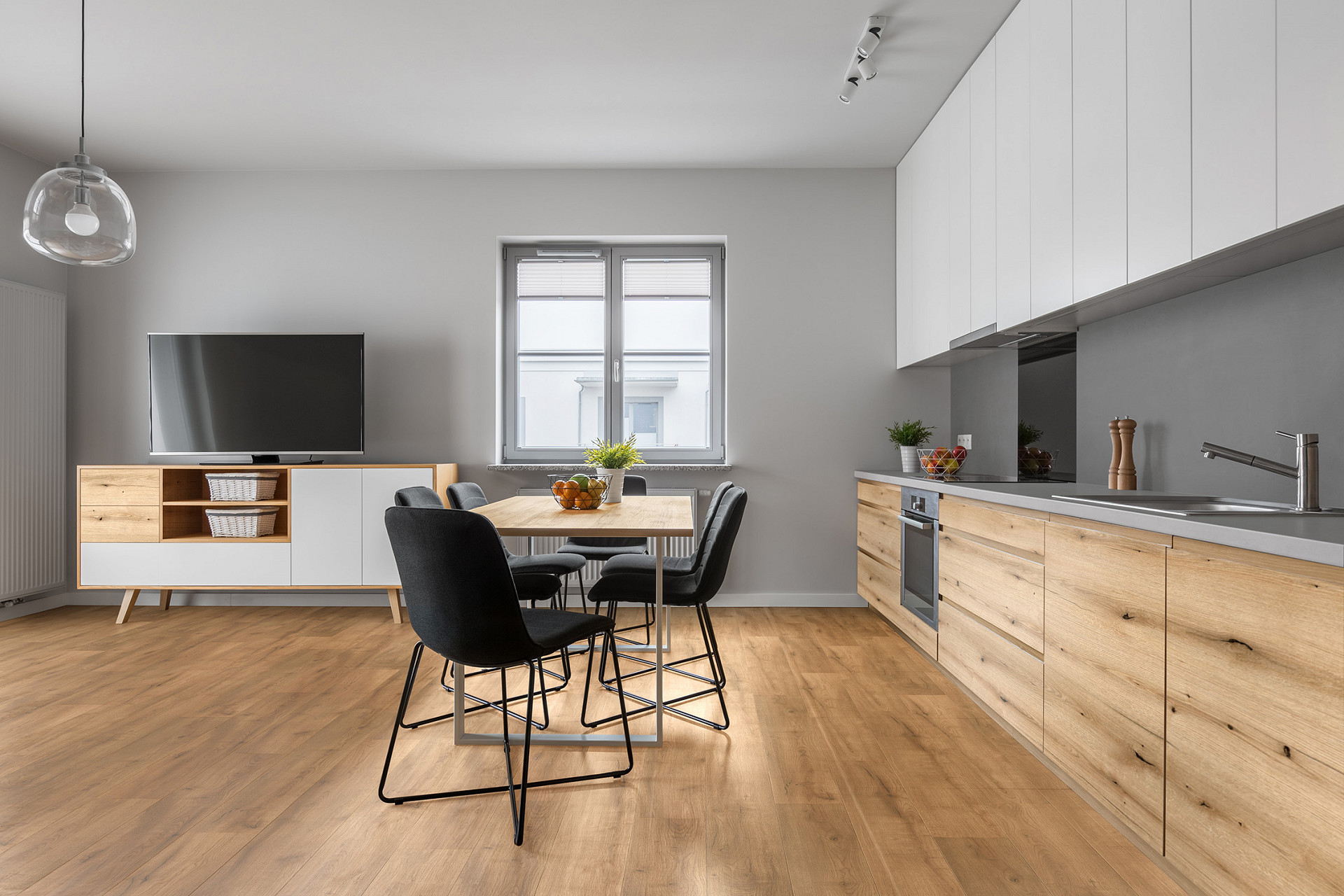 A stylish kitchen featuring Z209 Butterscotch Oak SPC flooring, complemented by a dining table, chairs, and a television.